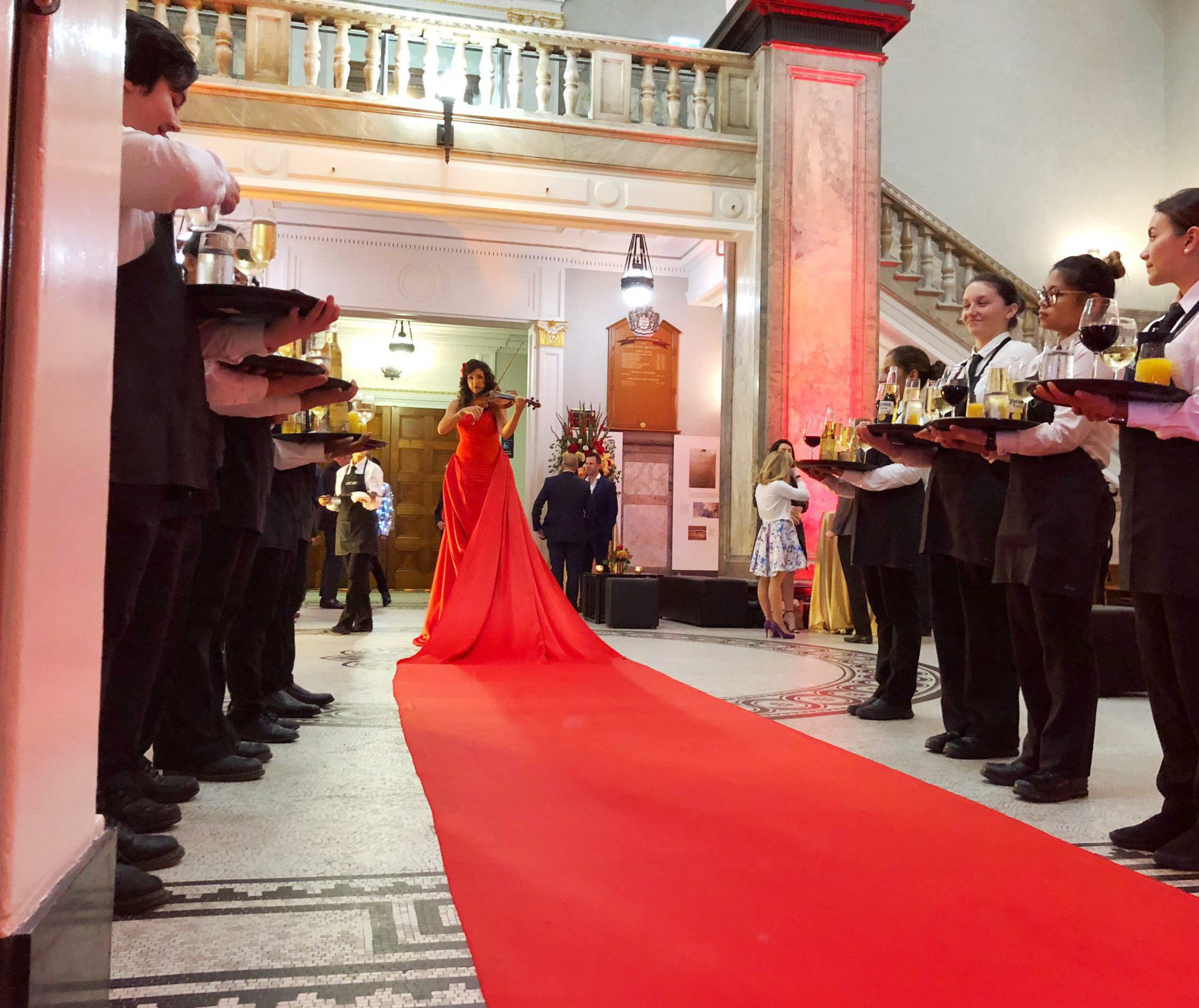 Lady wearing a very long red dress acting as a red carpet