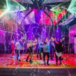 Guests dancing beneath colourful stage lighting and streamers at a professionally planned Brisbane event.