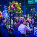 Themed gala dinner with roving performers, floral centrepieces and colourful event lighting.
