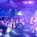 Live band entertaining guests on a packed wedding reception dance floor with stage lighting.