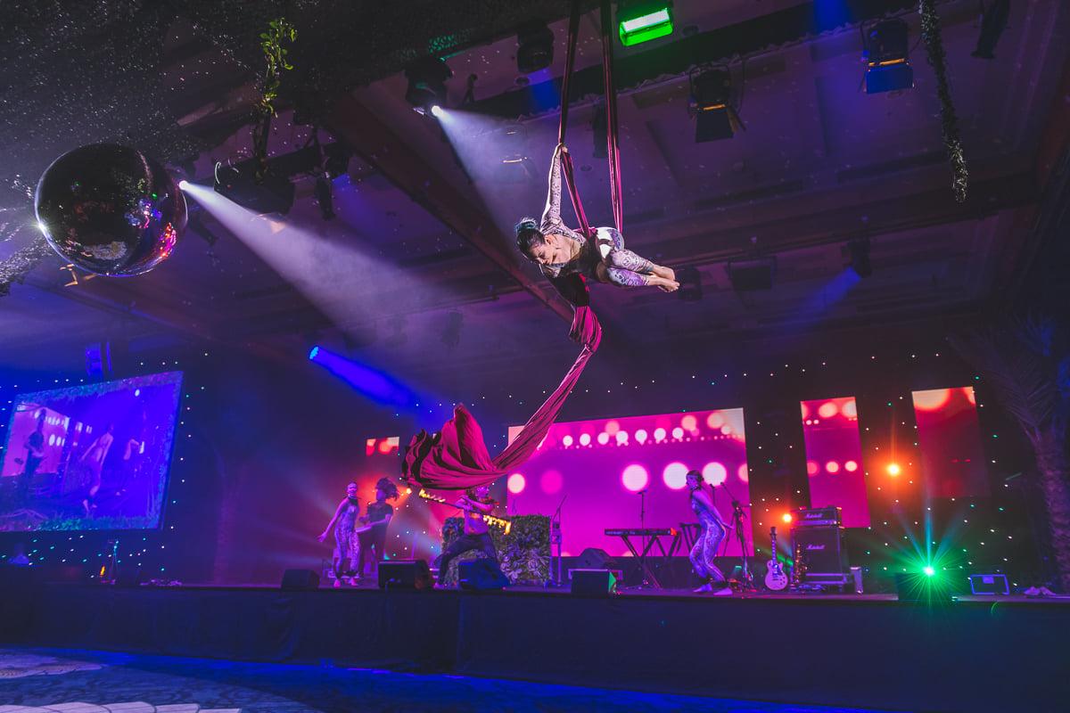Aerial performer above a corporate gala stage with LED screens and event lighting