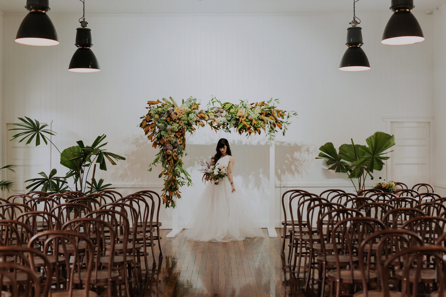 Wedding ceremony setup at Loyal Hope of the Valley Brisbane with timber floors, white VJ walls, bentwood chairs and floral arbour styling.