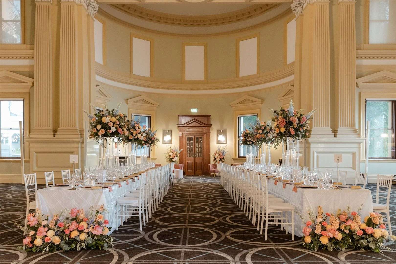 Wedding reception at Customs House Brisbane with long banquet tables, floral centrepieces and grand heritage architecture.