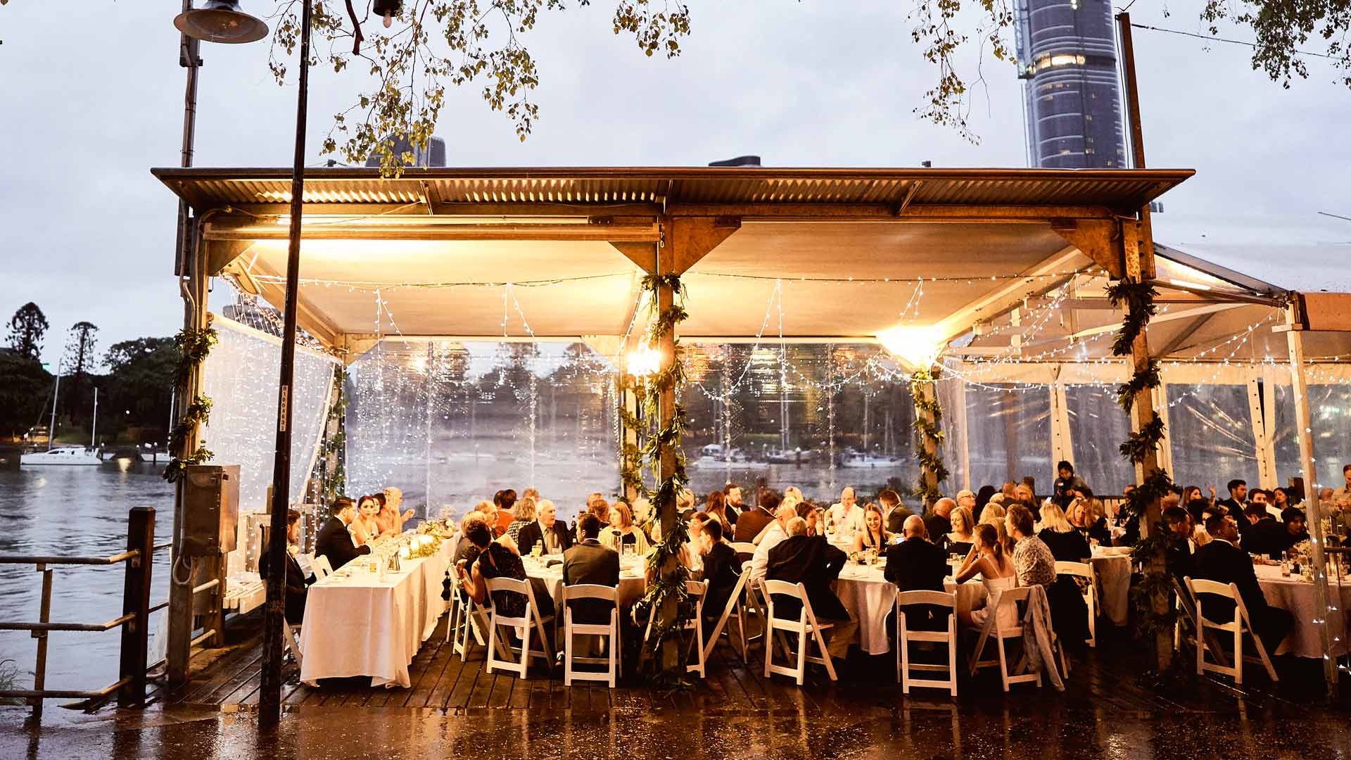 Riverside wedding reception at Riverlife Brisbane with marquee dining, city views and Brisbane River backdrop.