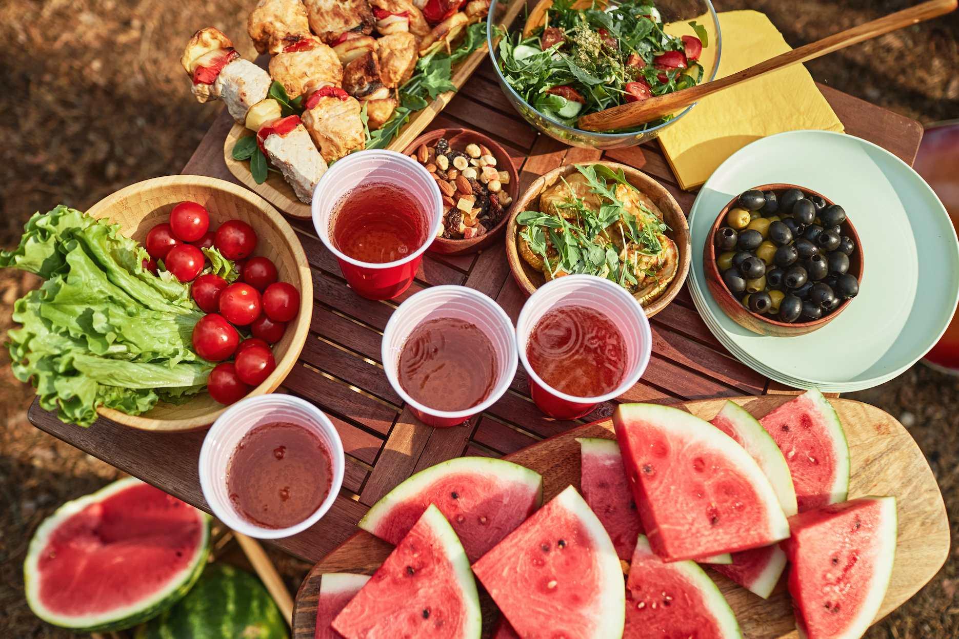 Summer party food table with fresh fruit, salads, skewers and drinks.