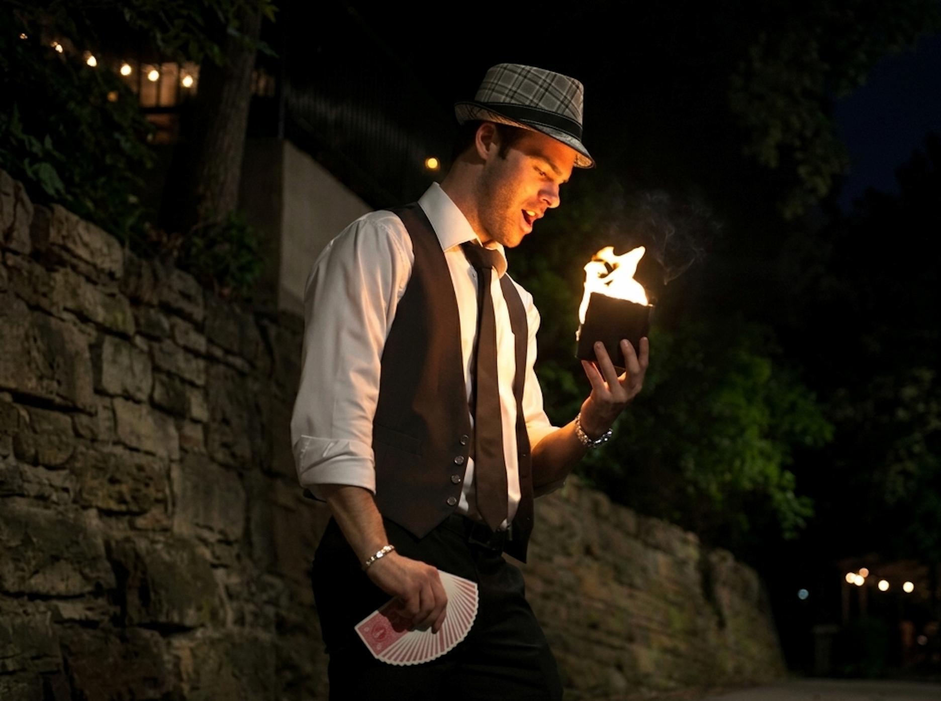 Magician performing close-up magic at an outdoor summer party.