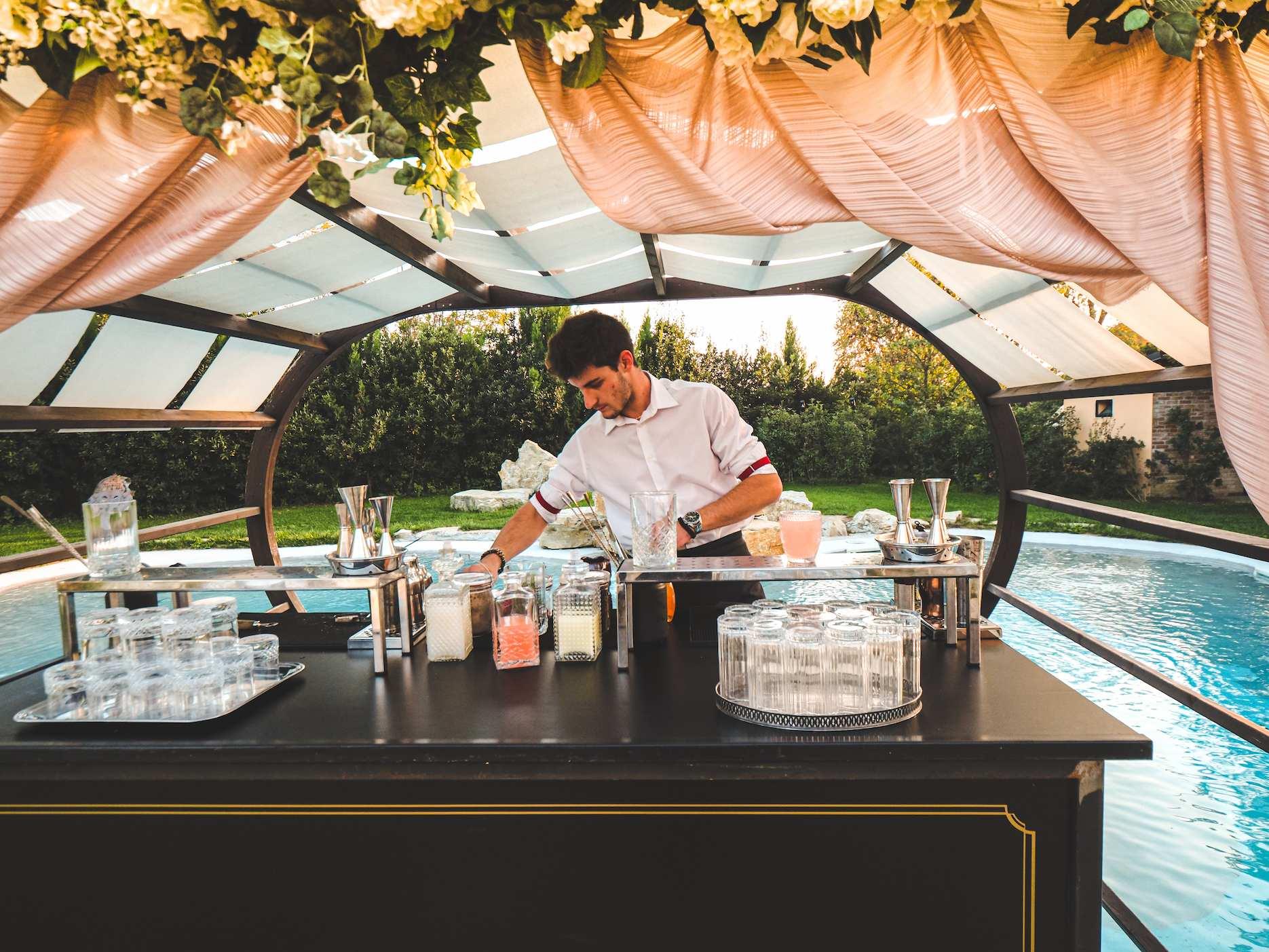Bartender serving drinks beside a pool for a summer party.