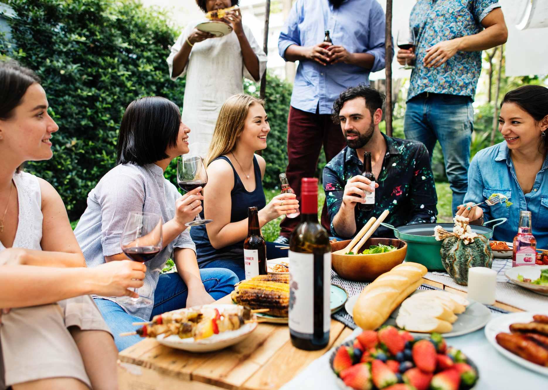 An outdoor summer party in Australia, with friends sharing food and drinks with smiles on their faces.