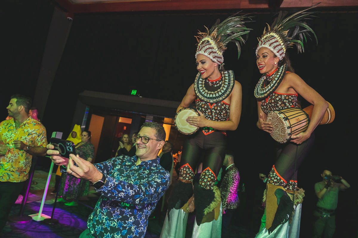 Corporate party guests watching an LED roving performer during a colourful cocktail event with aerial entertainment.