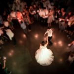 A couple doing their first dance at their wedding surrounded by love ones singing along to their wedding song.