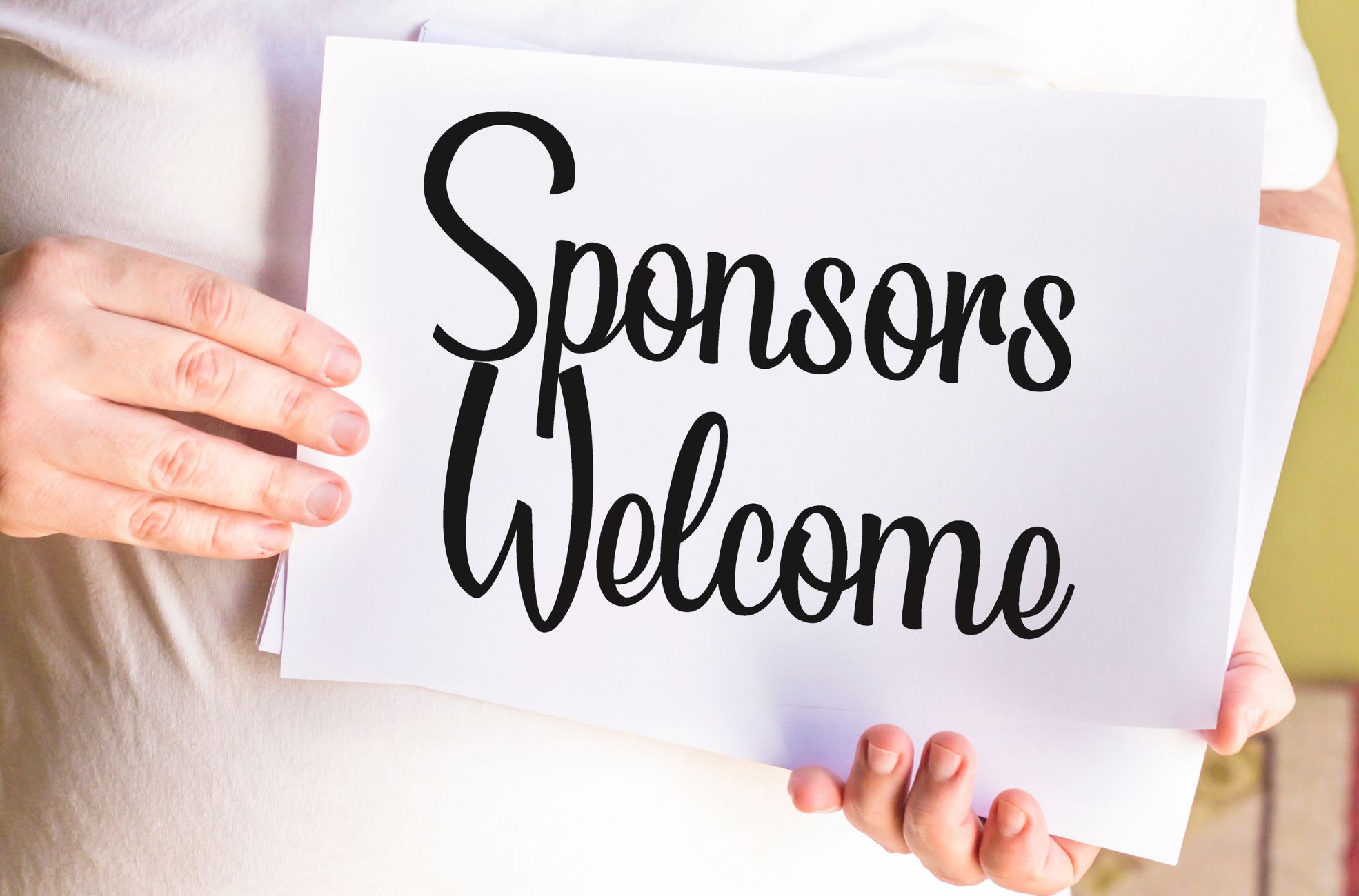 Person Holding Sign Saying Sponsors Welcome 