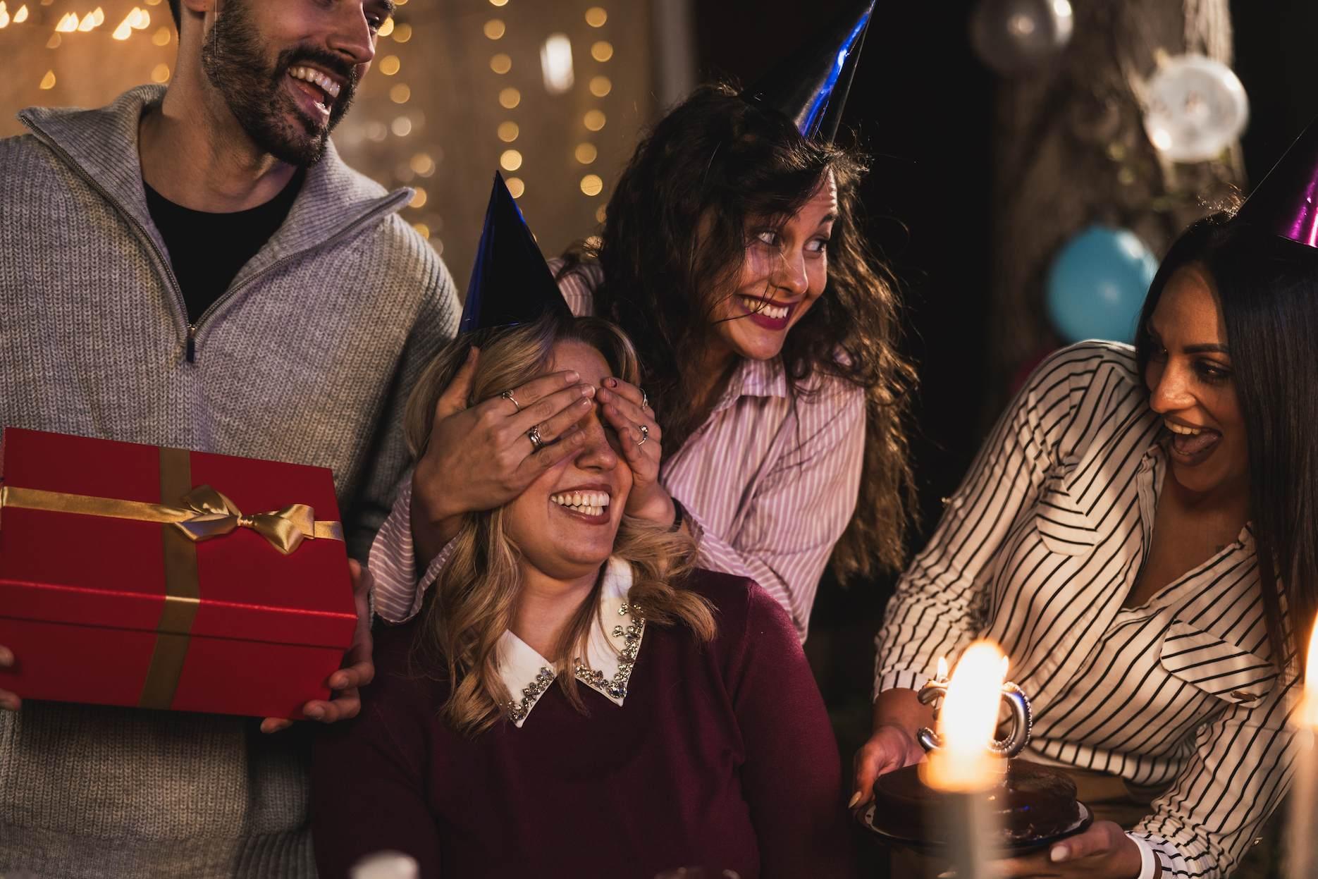 Friends planning a surprise birthday party with cake, gifts and party hats for the guest of honour.
