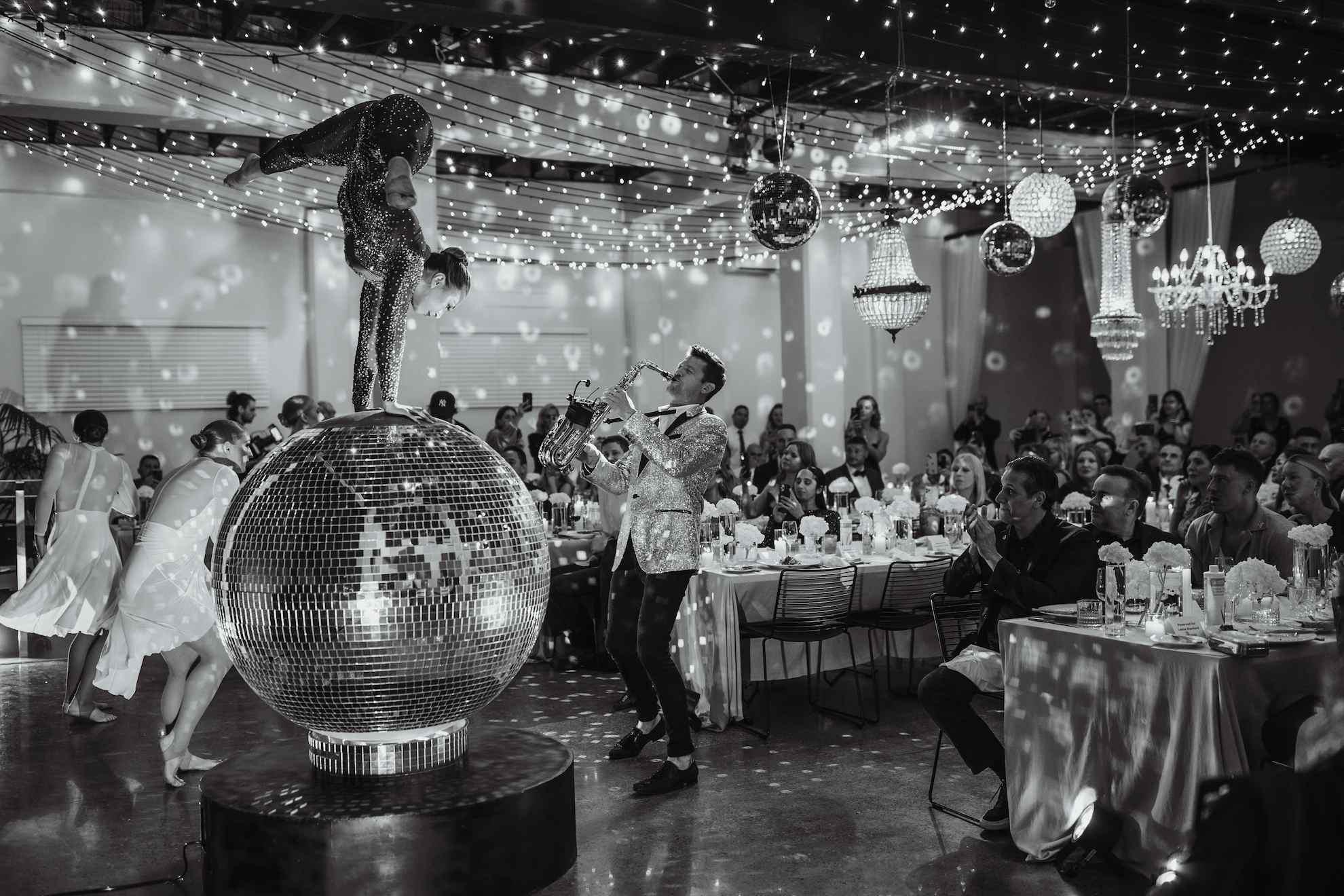A feature dancer doing a performance on top of a disco ball, while her supporting dancers dance around her.
