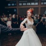 Bride and groom sharing their first dance at a wedding reception with guests watching.