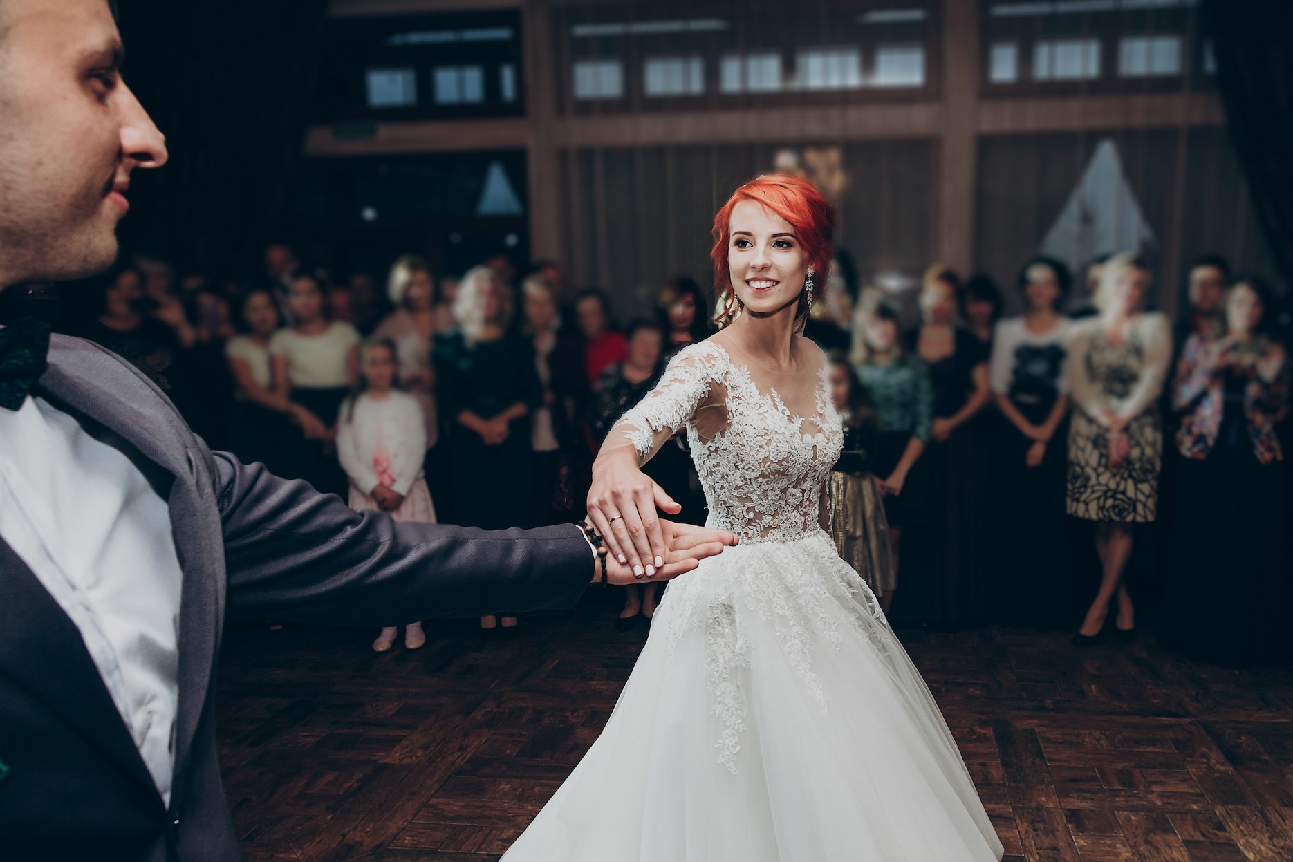 DJ-or-Wedding-Band Bride and groom sharing their first dance at a wedding reception with guests watching.