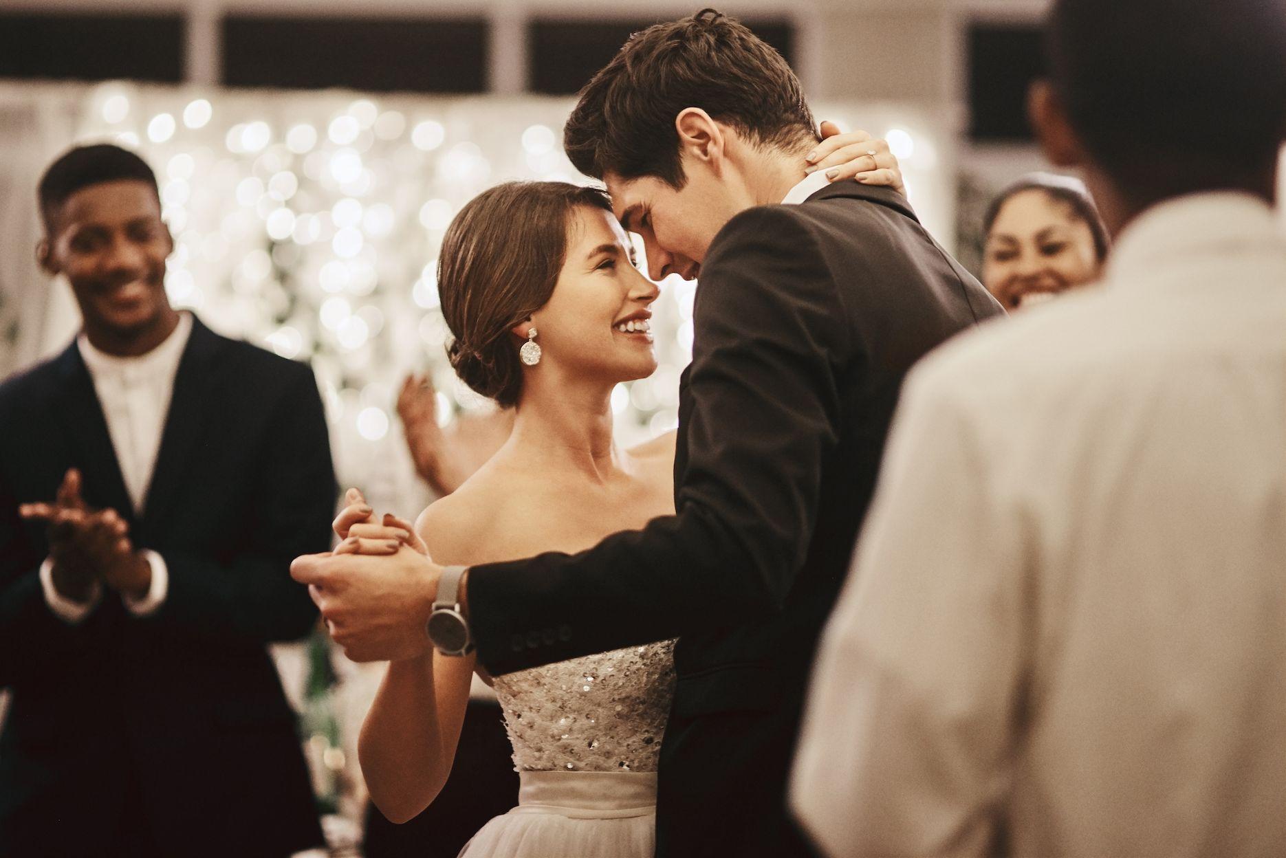 Newlywed couple sharing their first dance surrounded by wedding guests.
