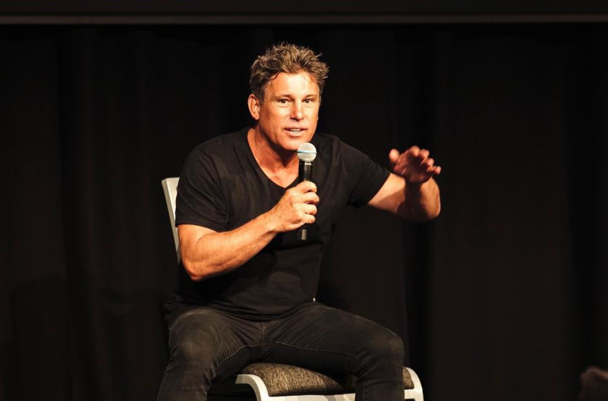 Male keynote speaker presenting with a handheld microphone at a corporate event in Australia.