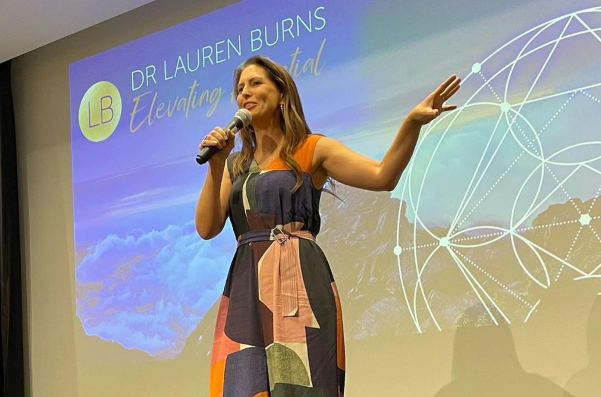 Female keynote speaker presenting on wellbeing and performance at a corporate event in Australia.