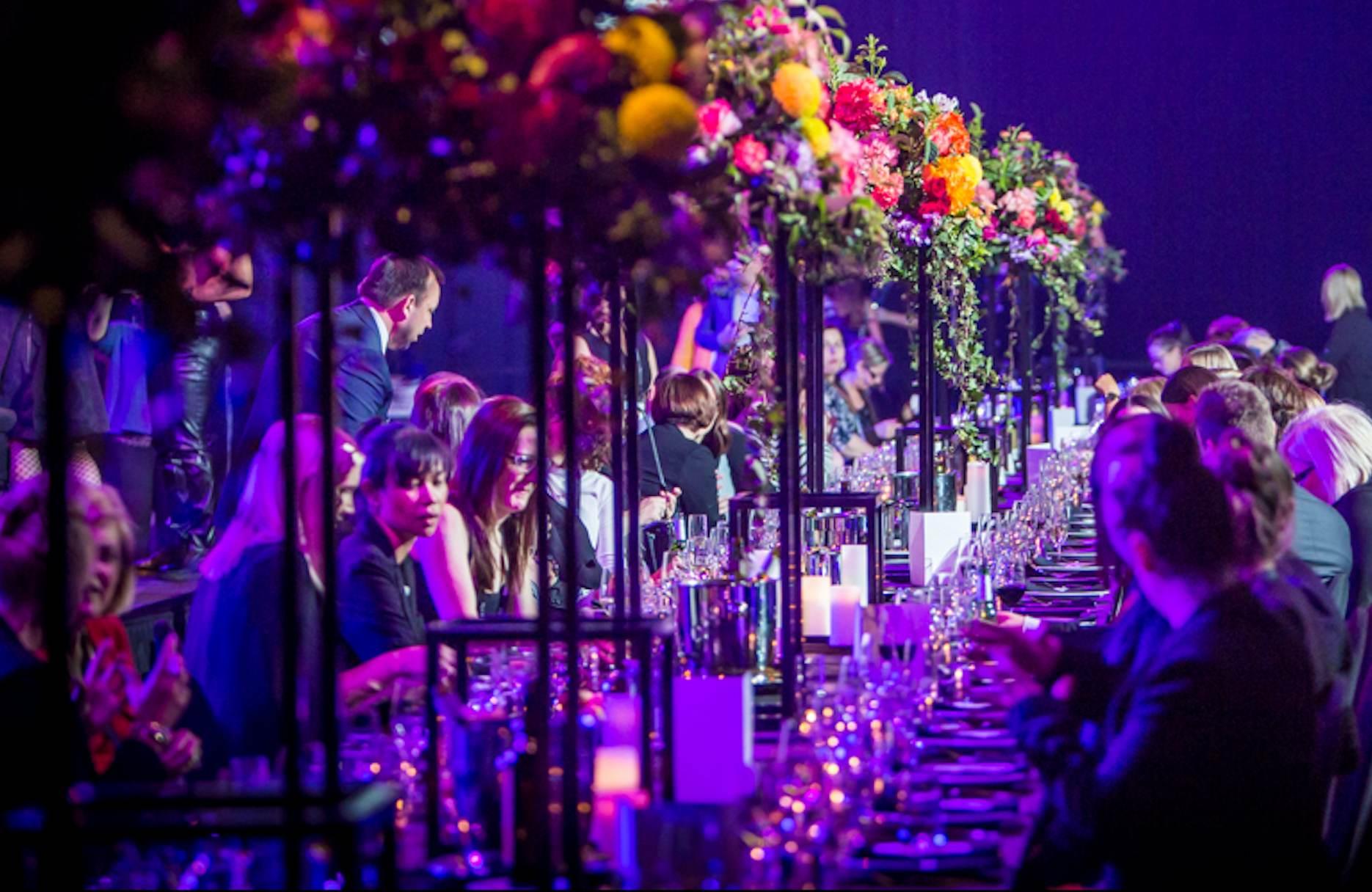 A long gala dinner table setup, with people enjoying their meals and drinks.