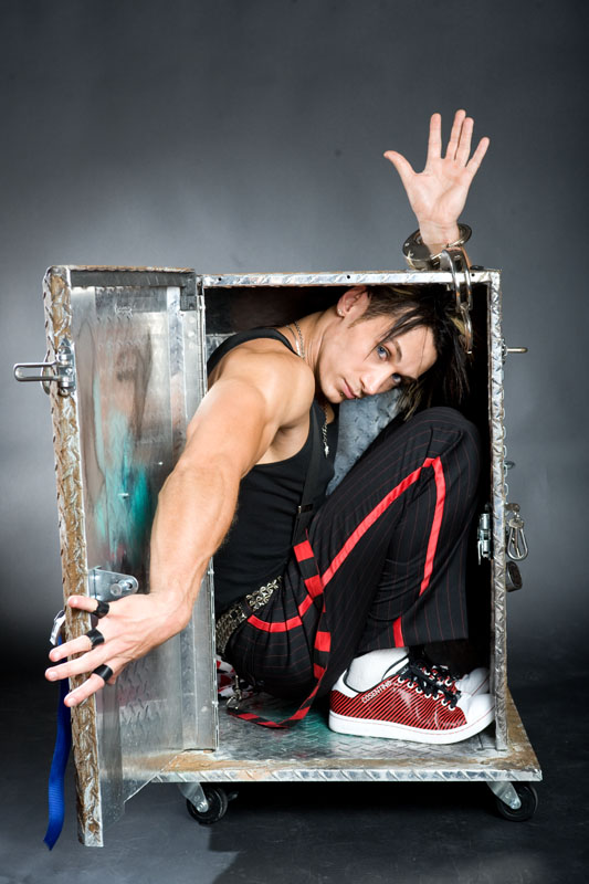 Onstage magician performing an escape illusion inside a metal box.