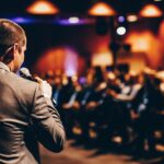 A corporate speaker in front of a crowd of people.