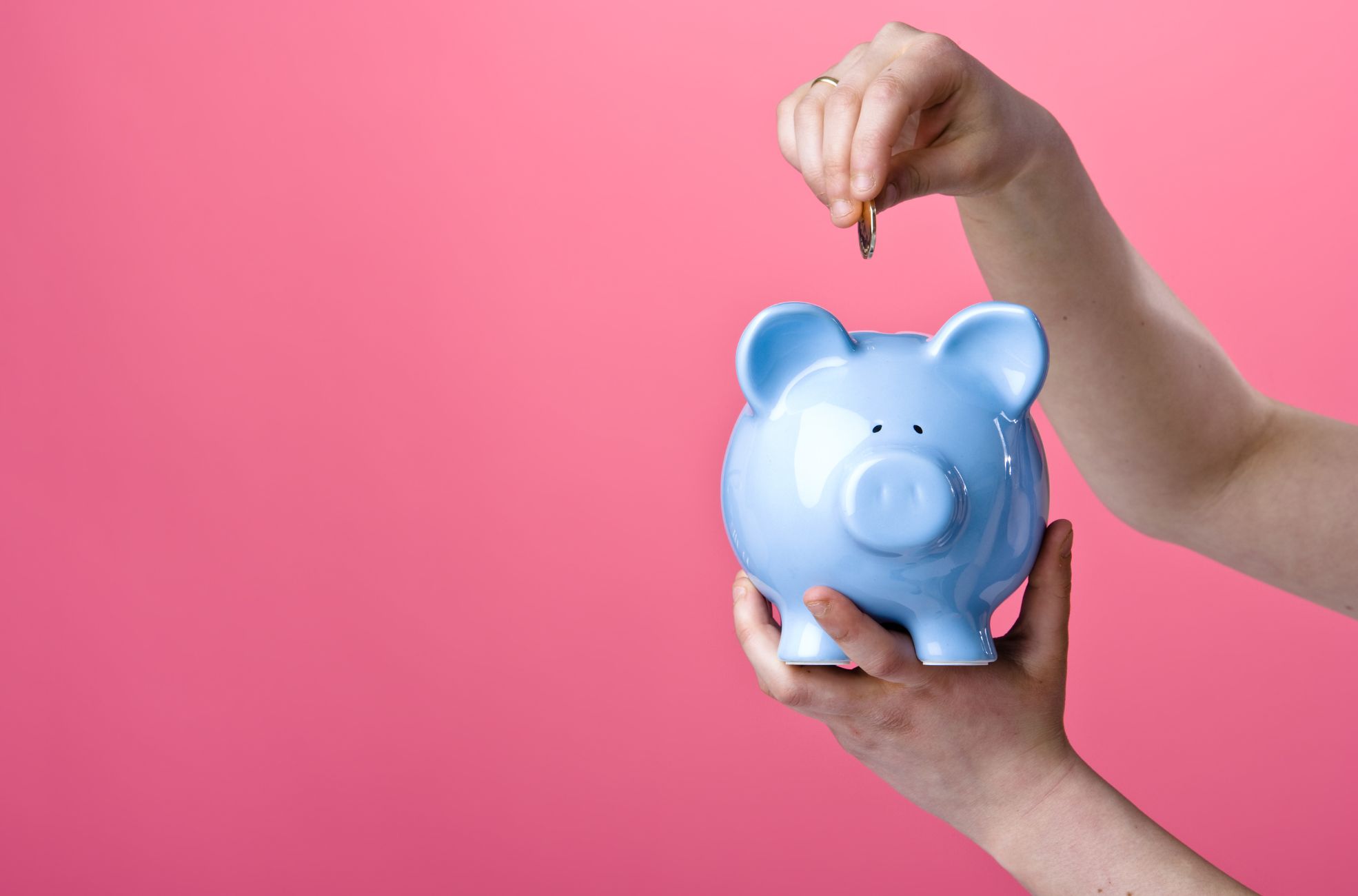 Woman Putting Money Into Piggy Bank