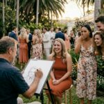Guests watching and laughing while a caricature artist draws at an outdoor party with relaxed social atmosphere.