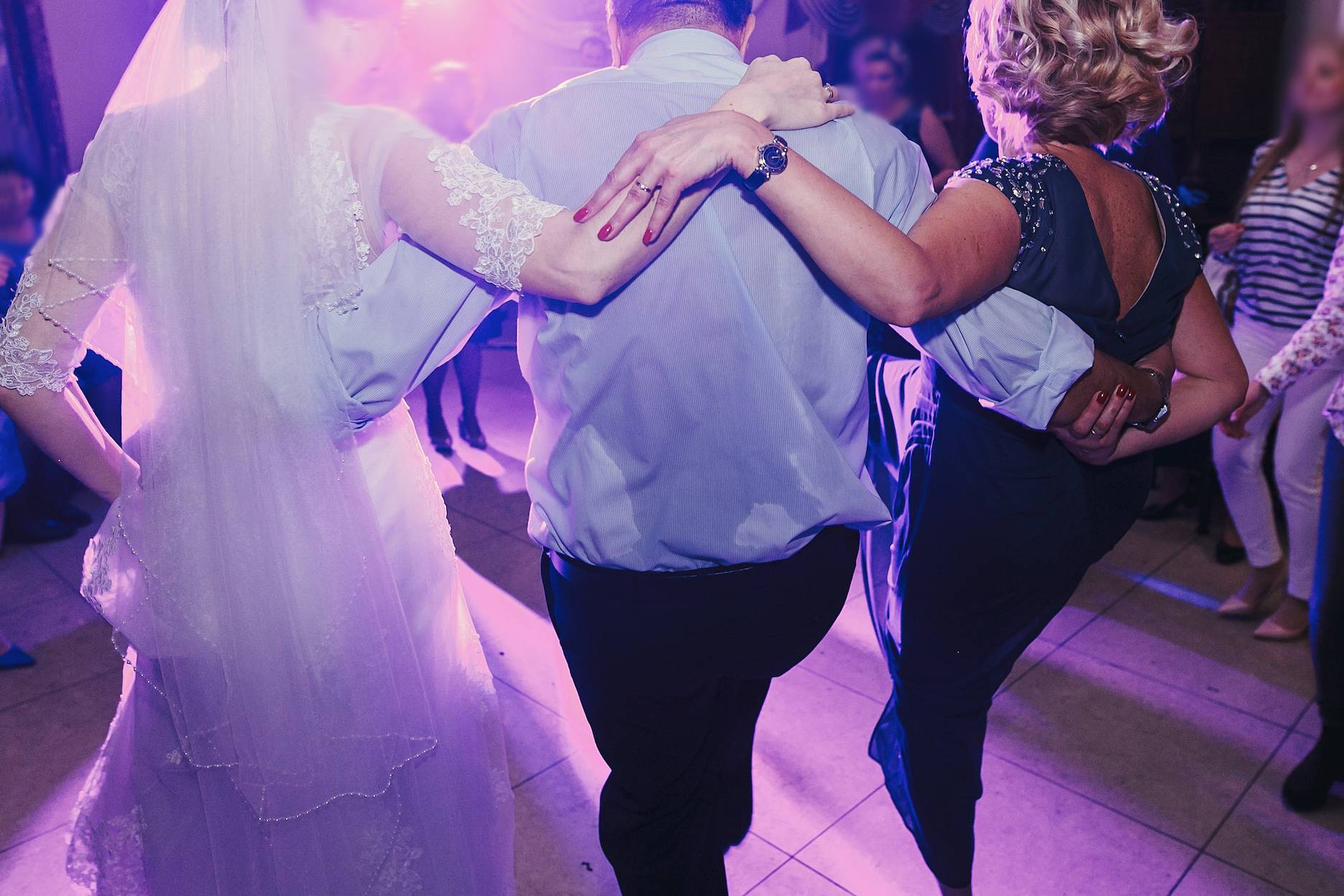 Wedding guests dancing together on a packed dance floor with friends and family celebrating.
