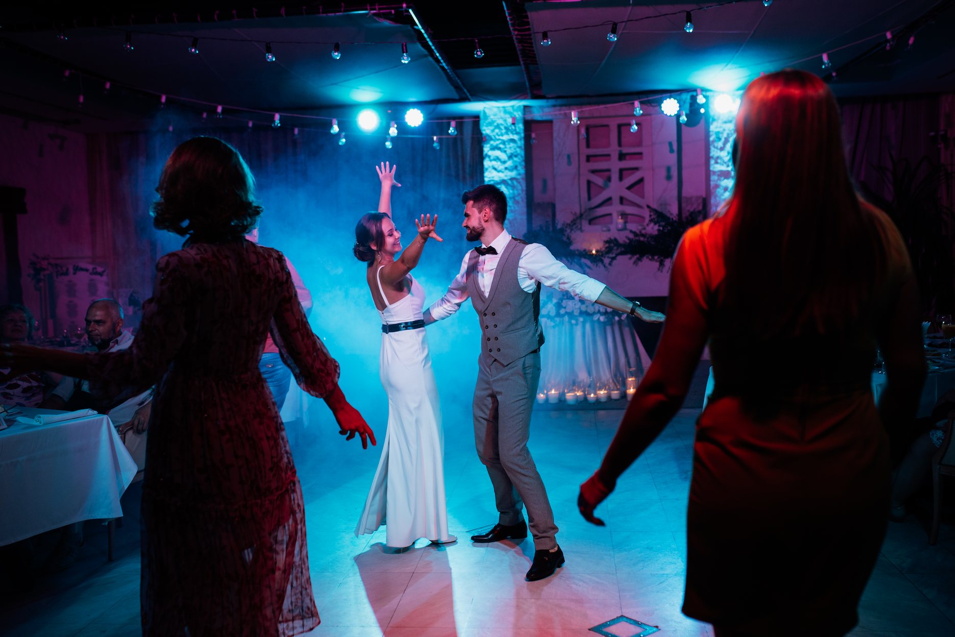 How-to-choose-the -ight-dj-for-your-wedding Bride and groom sharing their first dance at a wedding reception with atmospheric lighting and a lively dance floor.
