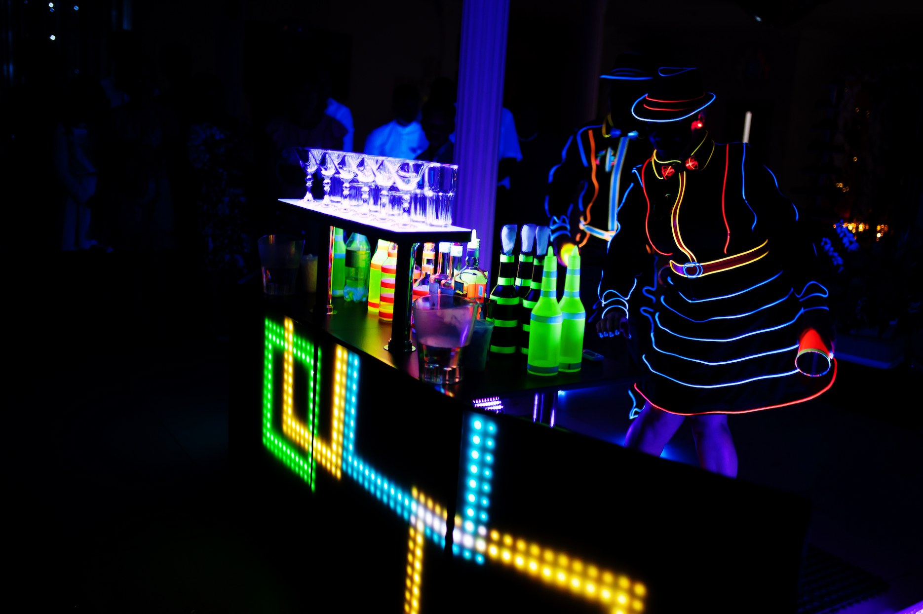 LED performer serving drinks at a neon-themed party event.