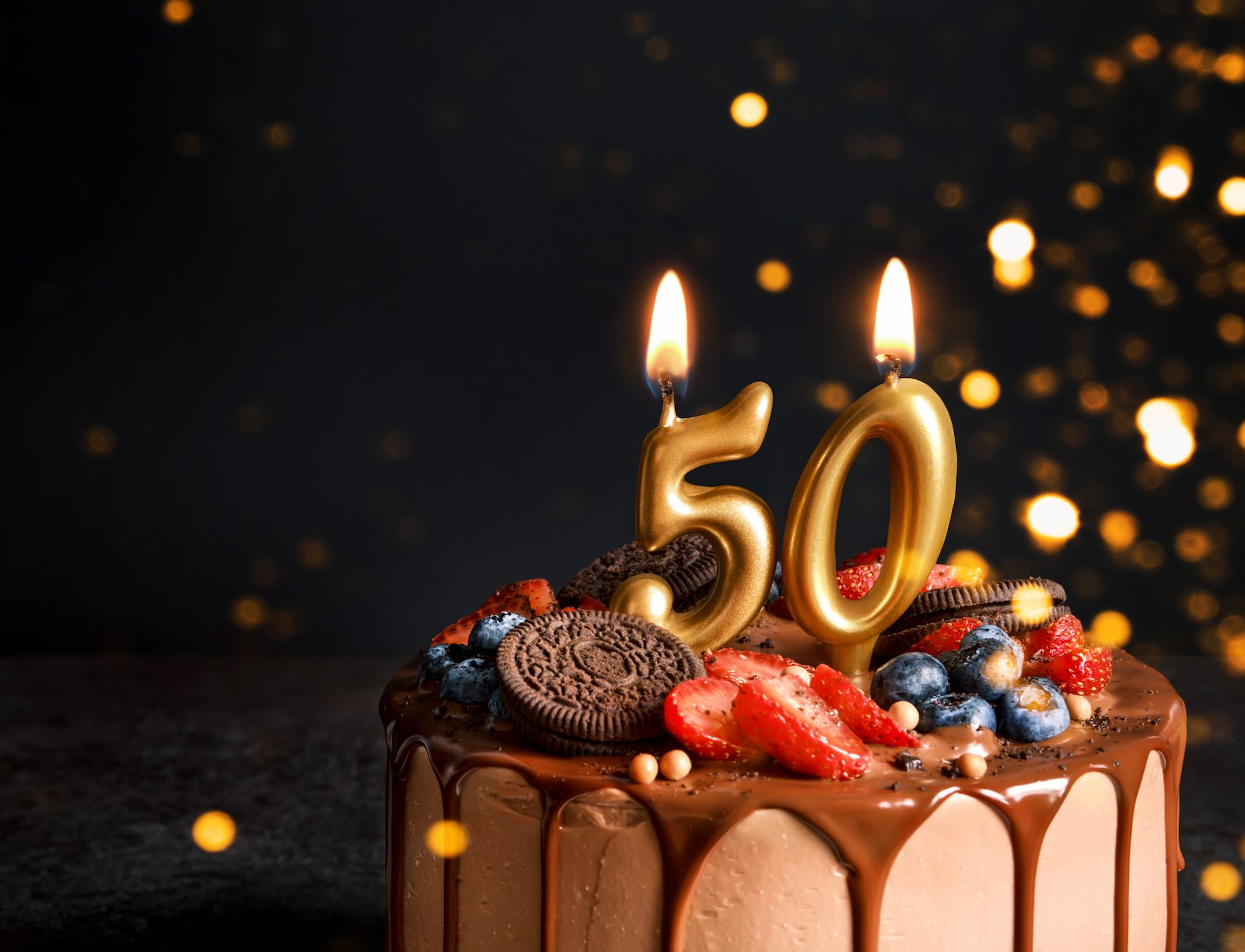 50th birthday cake with gold number candles and elegant celebration styling.