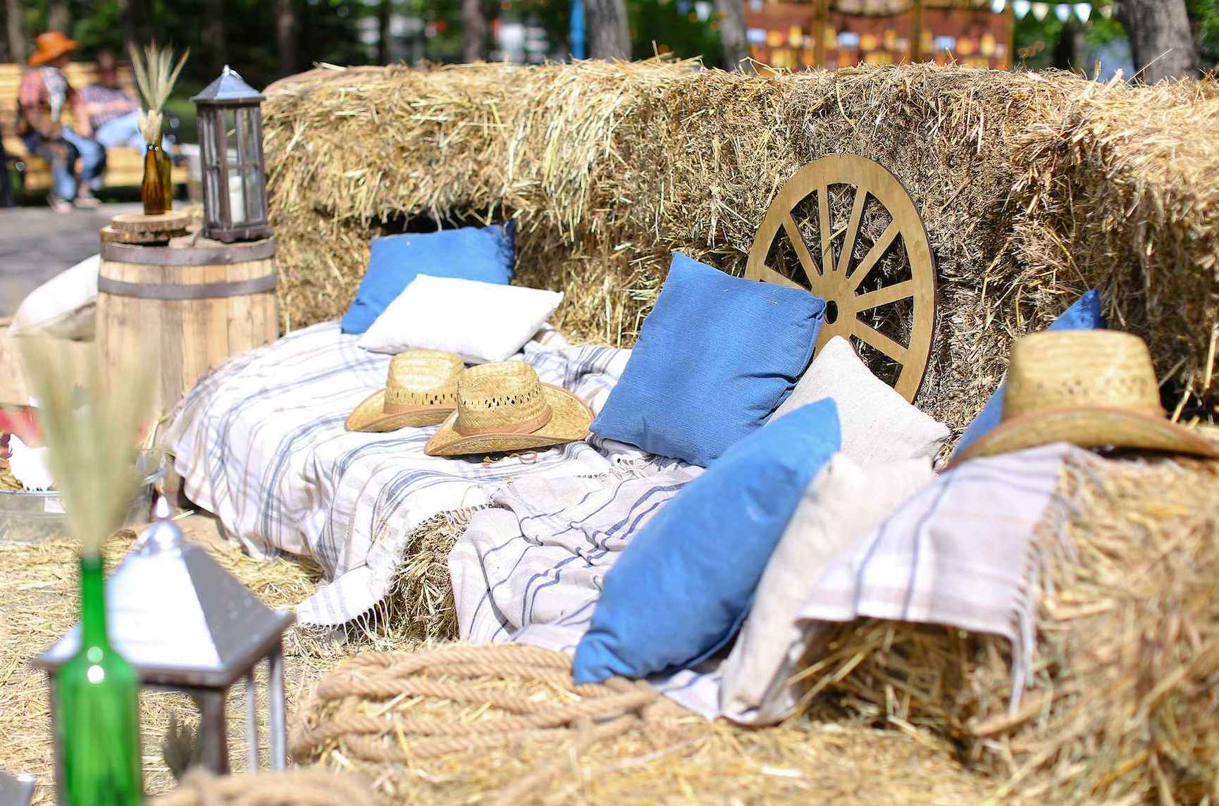 Country themed party decor with hay bale seating, rustic cushions, cowboy hats and outdoor styling setup.