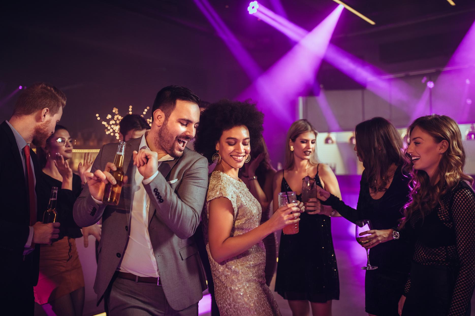 Guests dancing at a lively engagement party with drinks, party lighting and DJ-style entertainment.