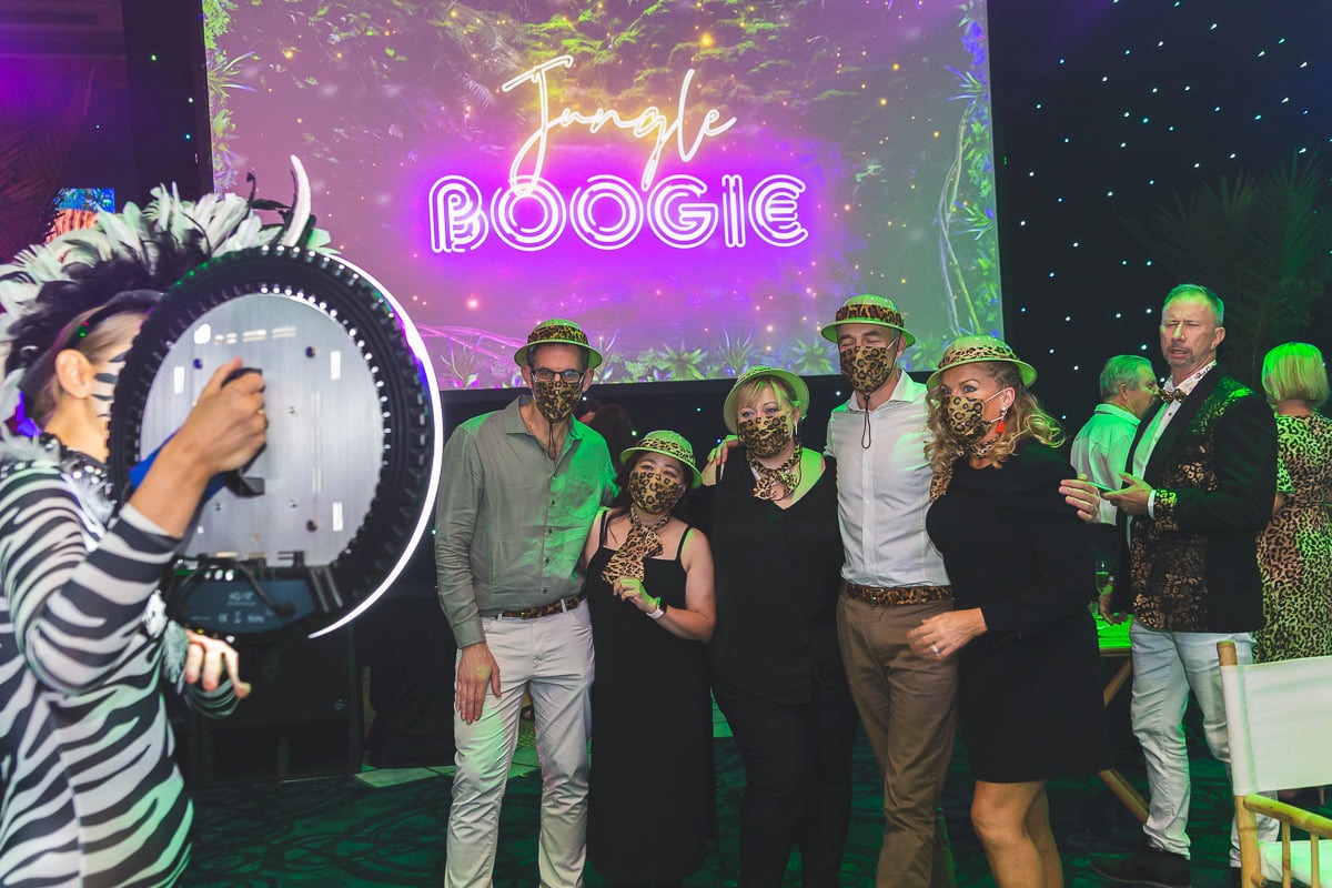 Guests posing with a zebra-costumed roving entertainer at a jungle-themed corporate event.
