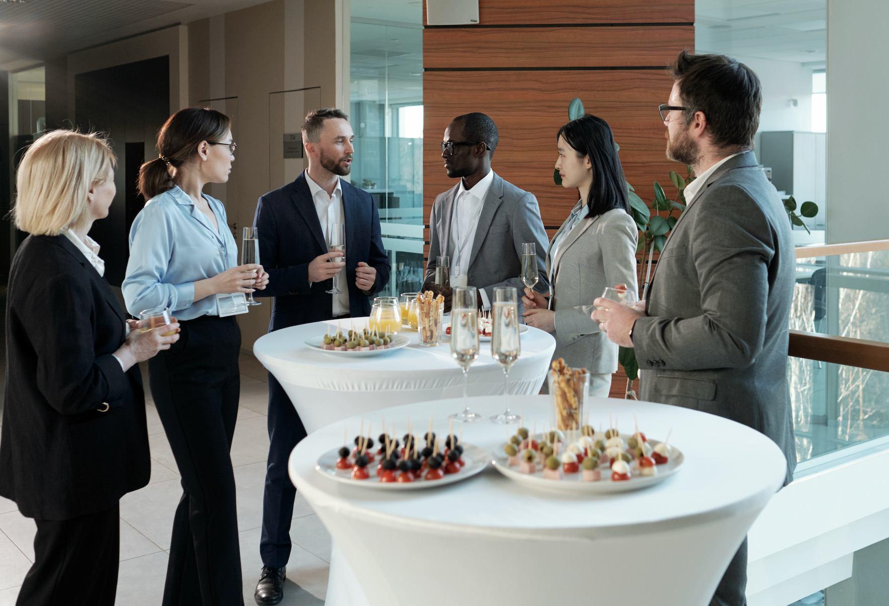 Professionals networking at a corporate function with drinks, canapés, and cocktail tables.