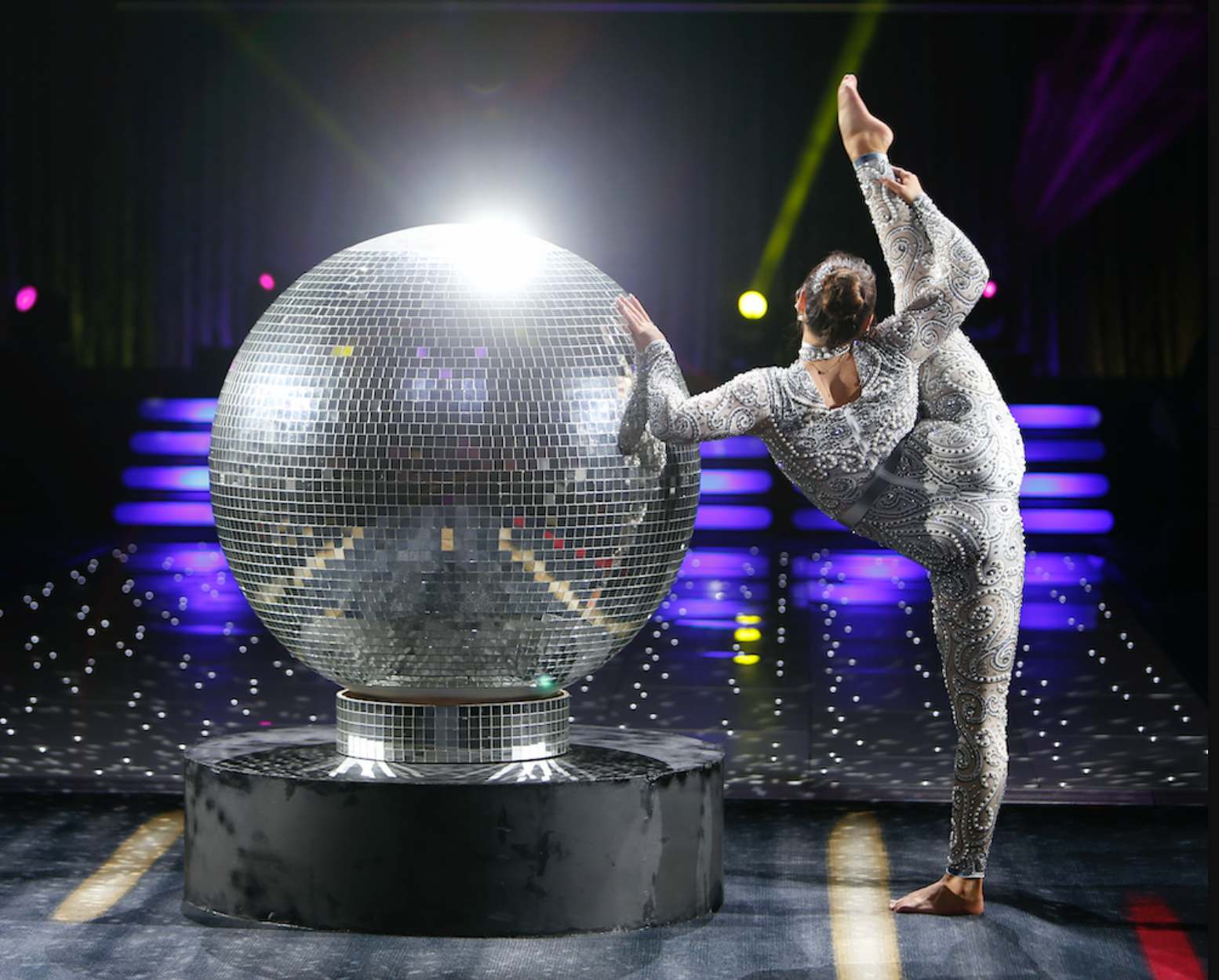 Disco-Theme-Party-3 Acrobat performing beside a giant disco ball at a disco theme party.