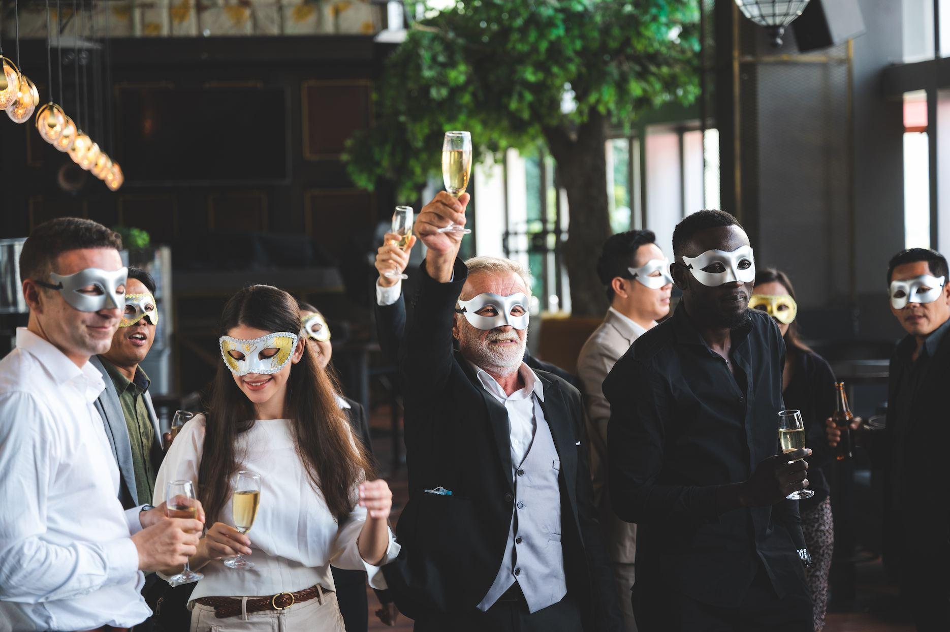 Guests wearing masks and raising drinks at a masquerade 40th birthday party.