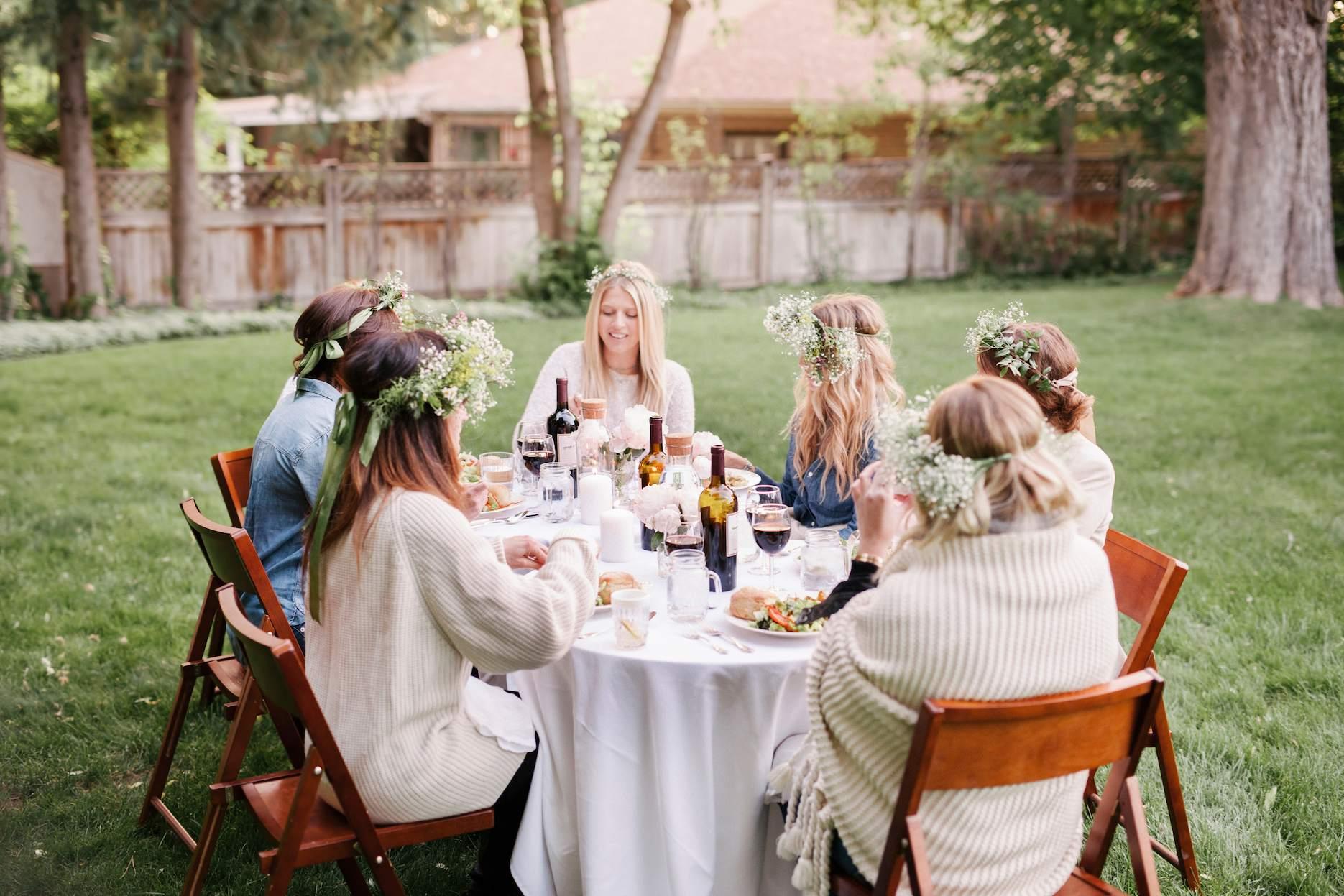 Women enjoying a garden party bridal shower around a decorated outdoor table.