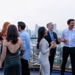 Staff party guests enjoying rooftop drinks at a city venue.