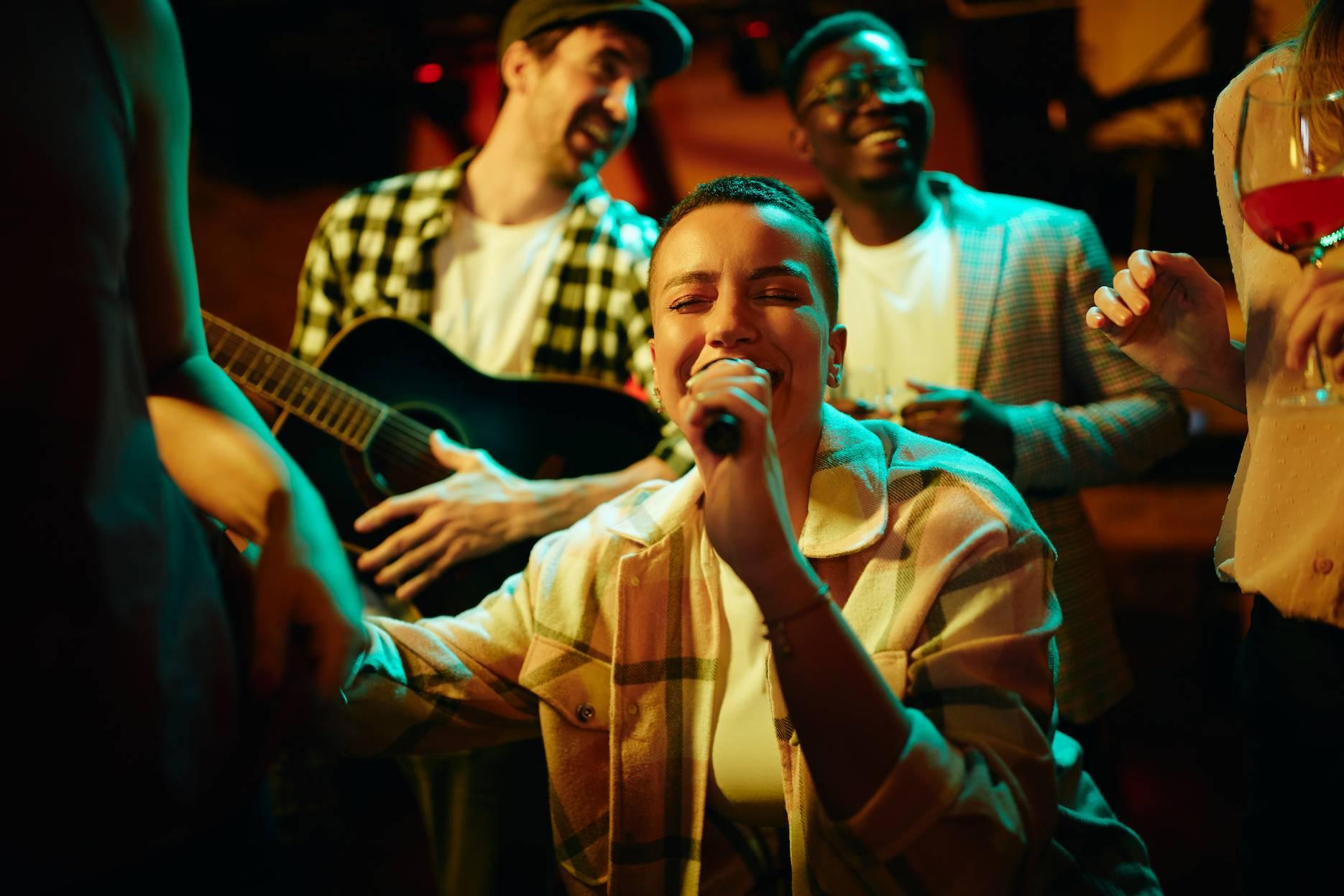 Party guests singing into a microphone with live music and colourful stage lighting.