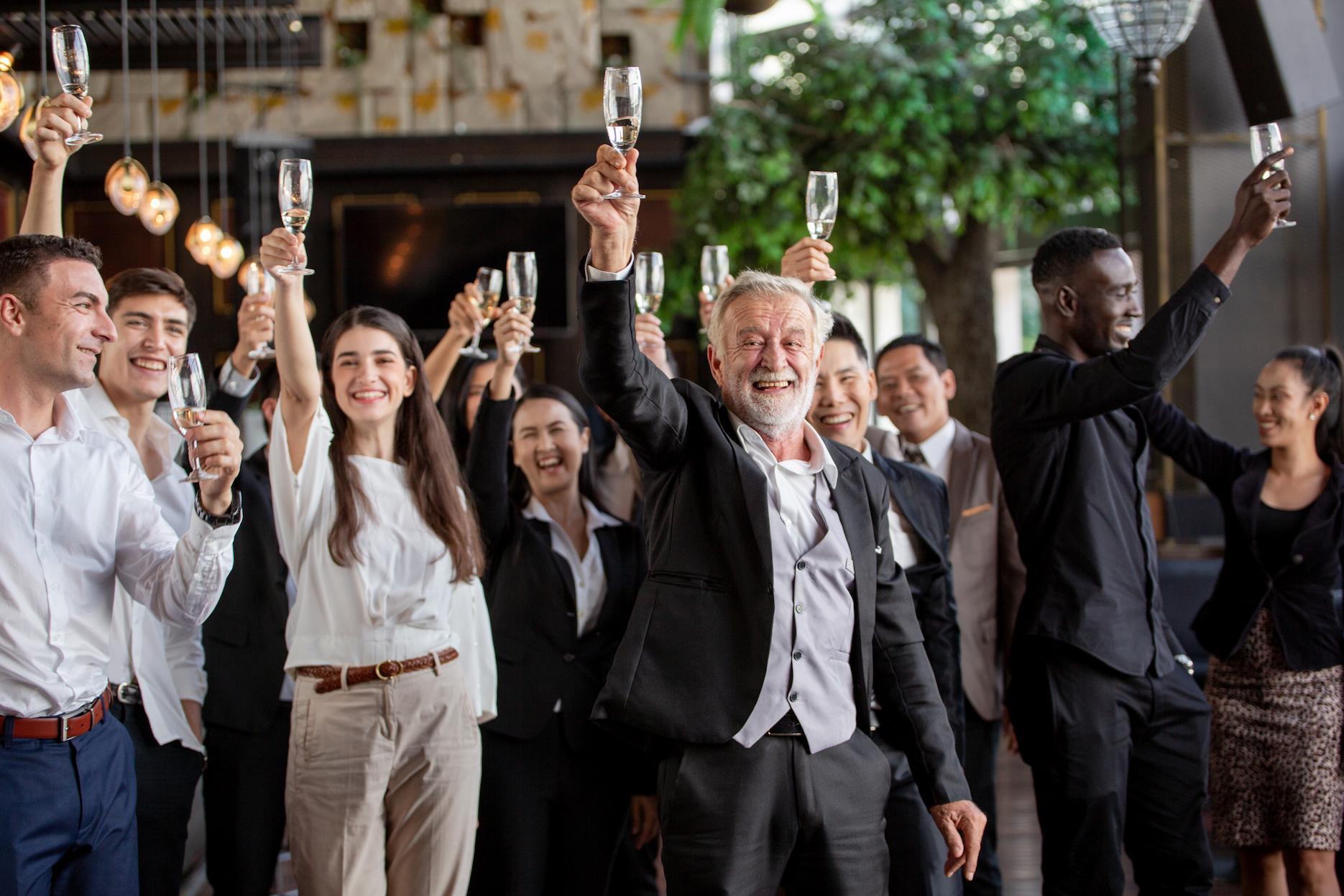 Guests smiling and raising their glasses together for a celebratory toast.