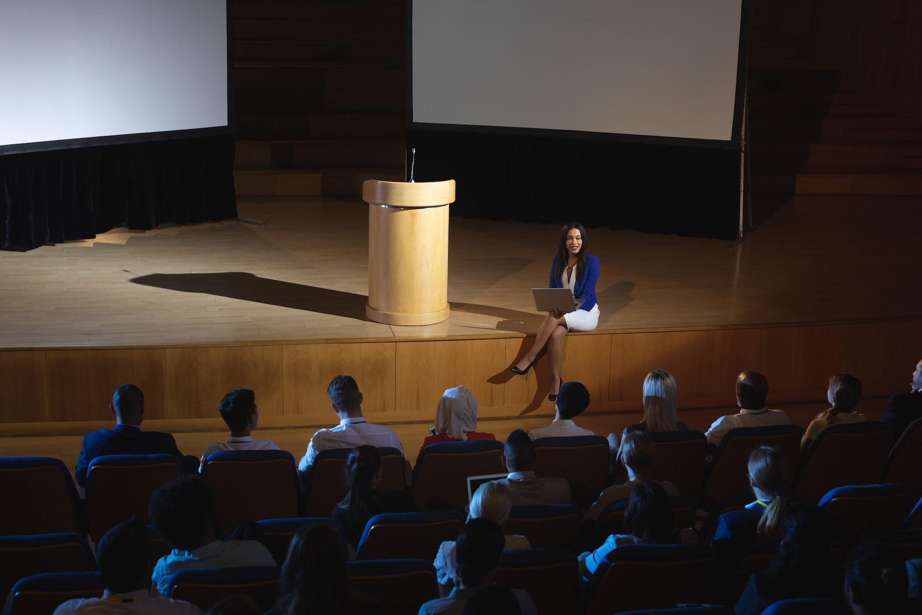 Business speaker presenting to a corporate audience during a conference session.