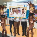 Onstage roving performers in tiger costumes posing with delegates at an APP 2022 trade show exhibition stand.