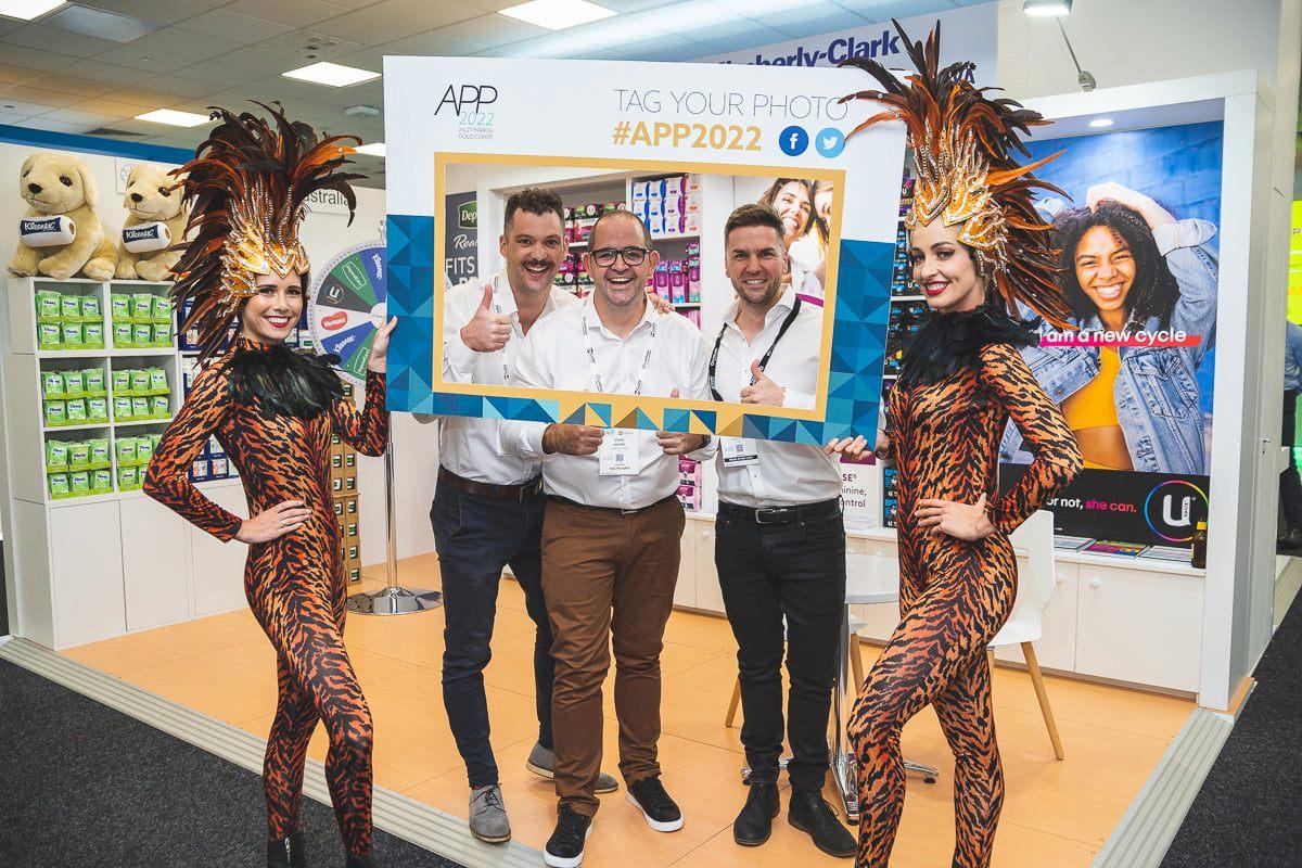 Trade-Show-Entertainment-Ideas Onstage roving performers in tiger costumes posing with delegates at an APP 2022 trade show exhibition stand.
